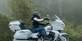 Motorcyclist wearing a helmet with a Hightail on it looking at the coast